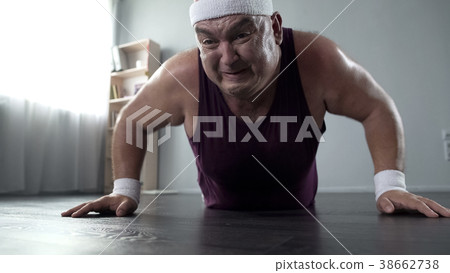 Motivated plump man in his 50s doing push-up with Motivated plump man in his 50s doing push-up with 38662738