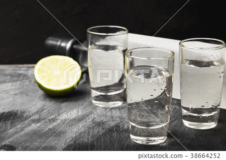 Cold vodka in shot glasses on a black background Cold vodka in shot glasses on a black background 38664252