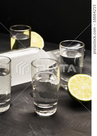 Cold vodka in shot glasses on a black background Cold vodka in shot glasses on a black background 38664255