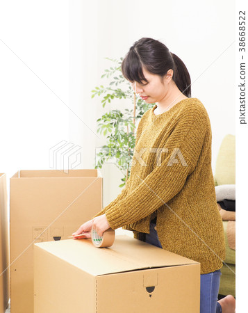 Woman closing a cardboard box with gum tape 38668522