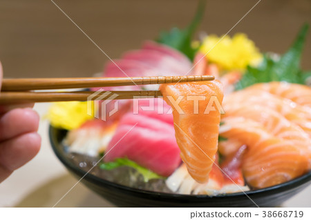 Chopsticks with Salmon sashimi with sliced fish Chopsticks with Salmon sashimi with sliced fish 38668719