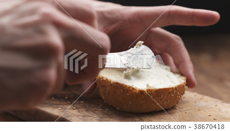 man hands spreading cream cheese on sesame bun on man hands spreading cream cheese on sesame bun on 38670418