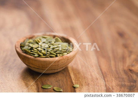 green pumkin seeds in bowl on wooden table 38670807