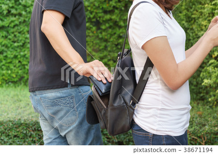 Thief trying to steal the wallet in the backpack Thief trying to steal the wallet in the backpack 38671194