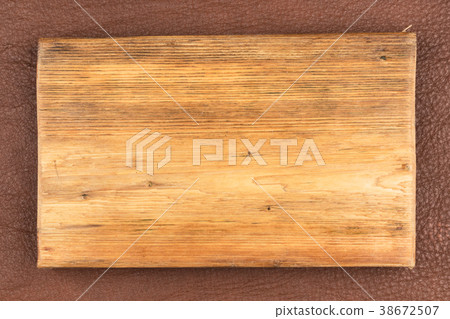 Rectangular board of light wood lies on  leather.. 38672507