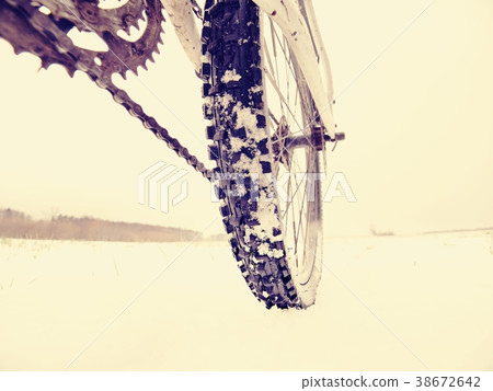Rear wheel of mountain bicycle in snowy meadow Rear wheel of mountain bicycle in snowy meadow 38672642