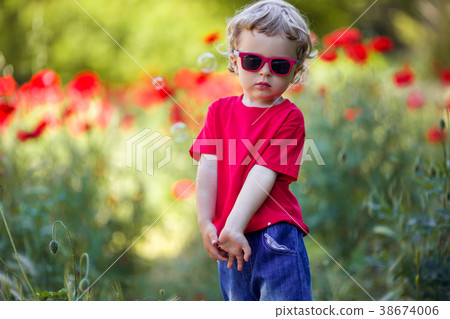 Pretty blond boy is wearing sunglasses holding red 38674006