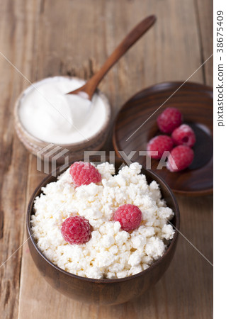 Cottage cheese with raspberry in wooden bowl Cottage cheese with raspberry in wooden bowl 38675409