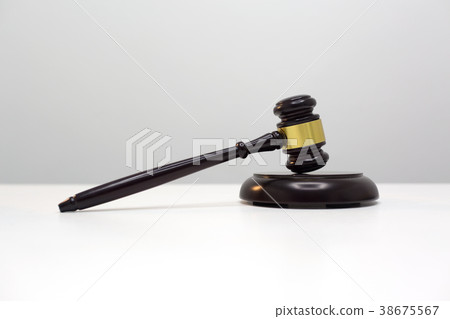 Dark wood gavel put on white table. 38675567