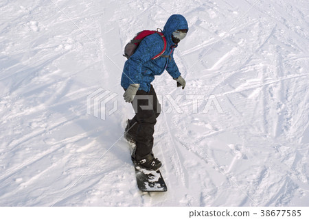 snowboarder is riding on a mountainside snowboarder is riding on a mountainside 38677585