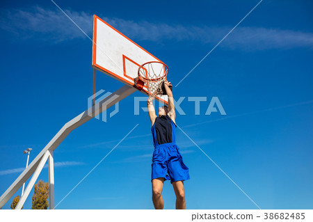 Young Basketball street player making slam dunk 38682485