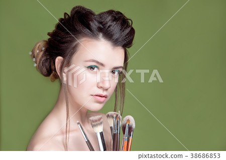 Closeup woman with makeup brushes near face Closeup woman with makeup brushes near face 38686853