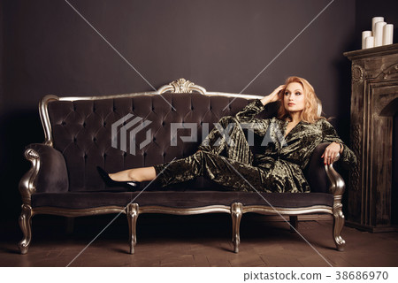 Beautiful woman on vintage couch near a fireplace  38686970