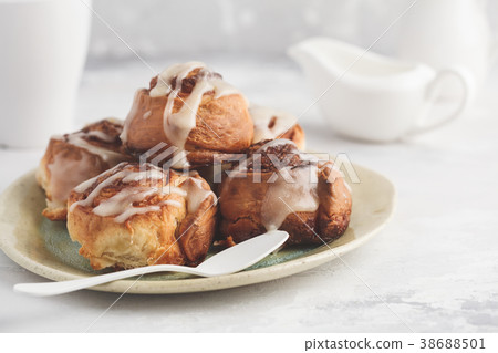 Homemade cinnamon buns in glaze on a light plate Homemade cinnamon buns in glaze on a light plate 38688501