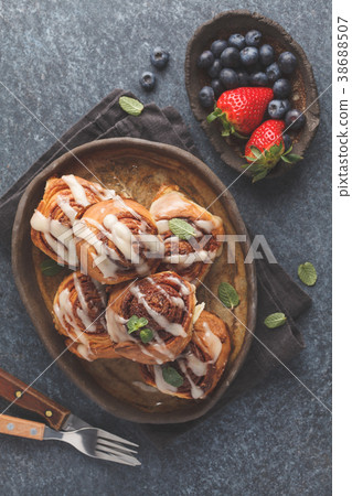 Homemade cinnamon buns in glaze on a dark plate Homemade cinnamon buns in glaze on a dark plate 38688507
