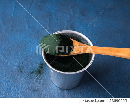 Spirulina powder in spoon on blue background 38690935