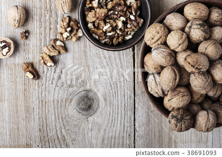 Walnut kernels in a  bowl and whole walnuts 38691093