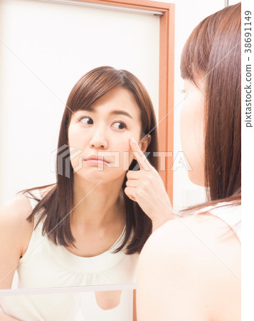 A woman troubled watching a mirror 38691149