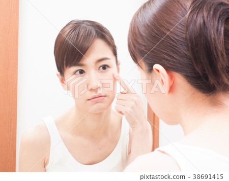A woman troubled watching a mirror 38691415