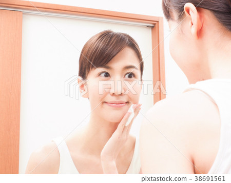 Woman looking at a mirror with cotton in hand Woman looking at a mirror with cotton in hand 38691561