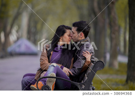 Young couple kissing on the bench in springtime Young couple kissing on the bench in springtime 38694368