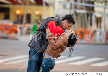 Young couple with heart shape toy kissing Young couple with heart shape toy kissing 38694386