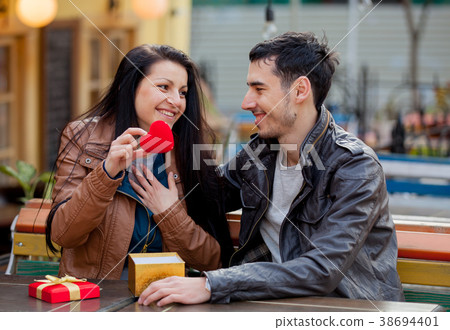 Young man giving a gift as to a young girl Young man giving a gift as to a young girl 38694401