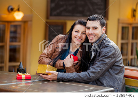 Young man giving a gift as to a young girl Young man giving a gift as to a young girl 38694402