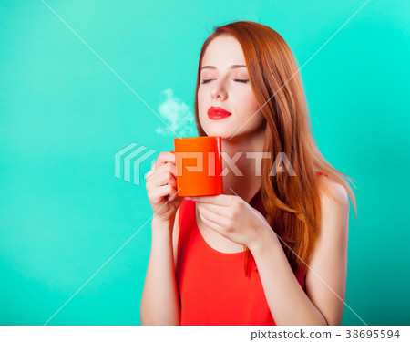 Redhead girl with coral cup of coffee or tea Redhead girl with coral cup of coffee or tea 38695594
