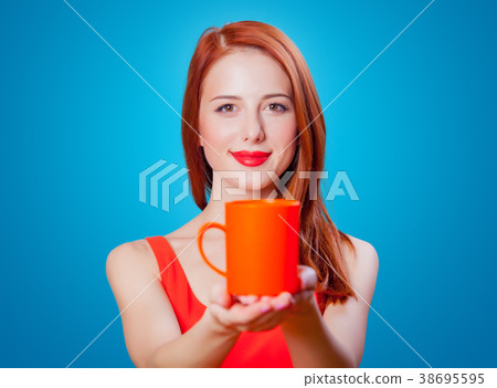Redhead girl with coral cup of coffee or tea Redhead girl with coral cup of coffee or tea 38695595