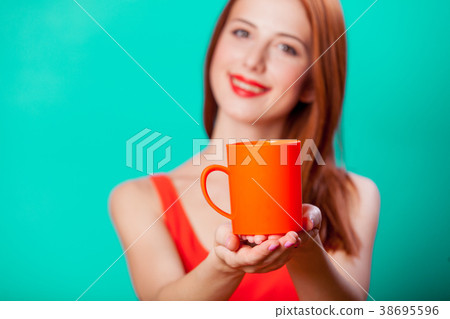 Redhead girl with coral cup of coffee or tea Redhead girl with coral cup of coffee or tea 38695596