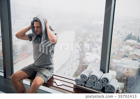 Young, tired man sitting on bench in a gym Young, tired man sitting on bench in a gym 38702413