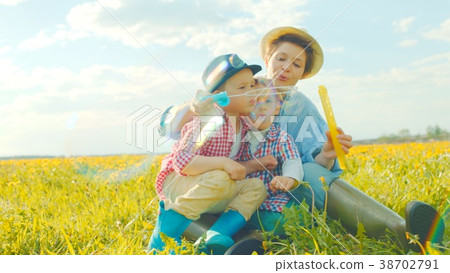 Little boys and their mother are blowing bubbles Little boys and their mother are blowing bubbles 38702791