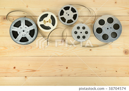 Obsolete cinema films on wooden surface of table. 38704574