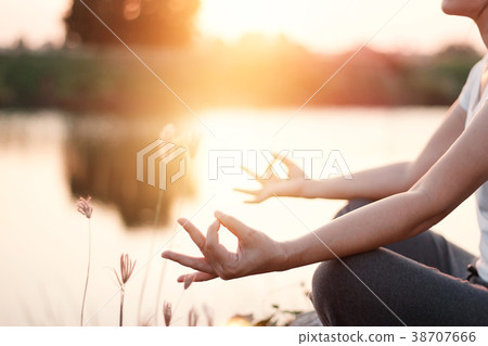 Woman practicing yoga meditating by lake in summer 38707666