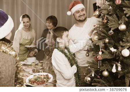 Family decorating Christmas tree and setting table 38709076