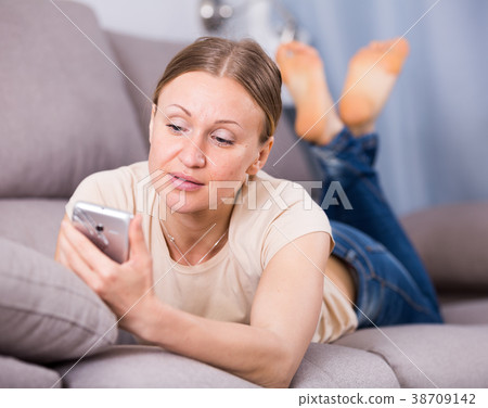 Woman lying on sofa with phone Woman lying on sofa with phone 38709142