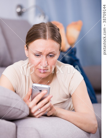 Woman looking at phone on sofa 38709144