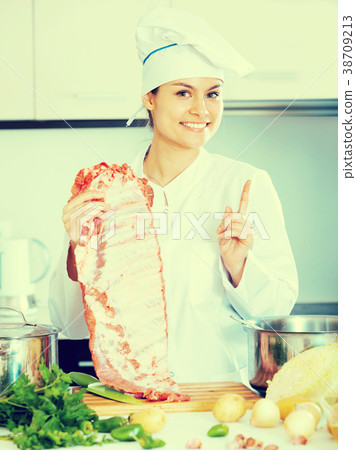Positive female chef working with pork ribs 38709213