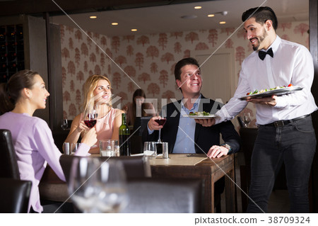 waiter bringing ordered dishes to guests waiter bringing ordered dishes to guests 38709324