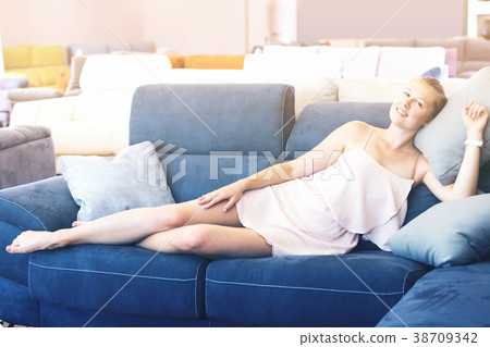 Glad woman lying barefoot on sofa with pillow Glad woman lying barefoot on sofa with pillow 38709342