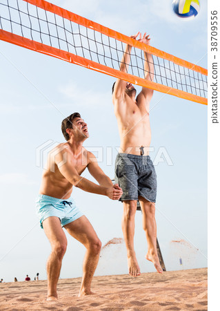 Adult men are jumping with ball in time play in volleyball Adult men are jumping with ball in time play in volleyball 38709556