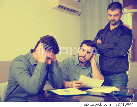 Three upset males with papers at table Three upset males with papers at table 38710044