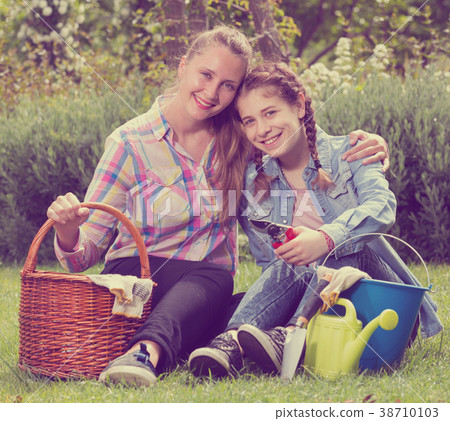 young mother and dauther with gardening tools in outdoors young mother and dauther with gardening tools in outdoors 38710103