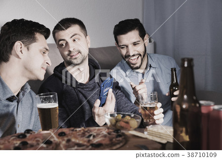 Male friends sitting with phone at home 38710109