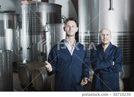 Two men in uniforms standing in winery fermentation compartment 38710230