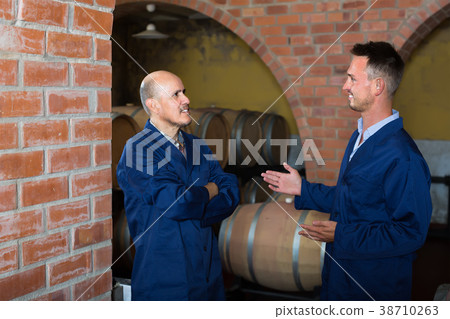 two friendly men in uniforms standing in cellar with wine woods 38710263