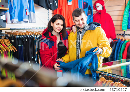 Couple examining track jackets in sports clothes store 38710327