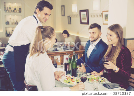 Handsome waiter serving meals to friendly company visitors Handsome waiter serving meals to friendly company visitors 38710387