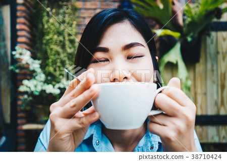 Asian women relax with white latte art coffee cup Asian women relax with white latte art coffee cup 38710424